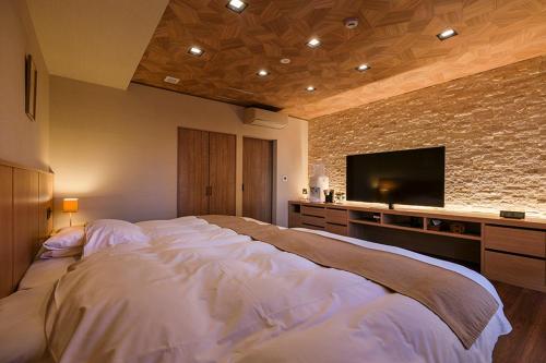 a bedroom with a large bed with a flat screen tv at Ryokusuitei in Kamogawa
