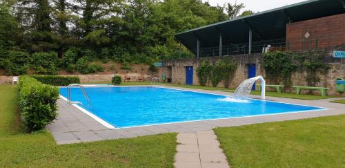 a large blue swimming pool with a water fountain at Camping Officiel Wollefsschlucht Echternach in Echternach