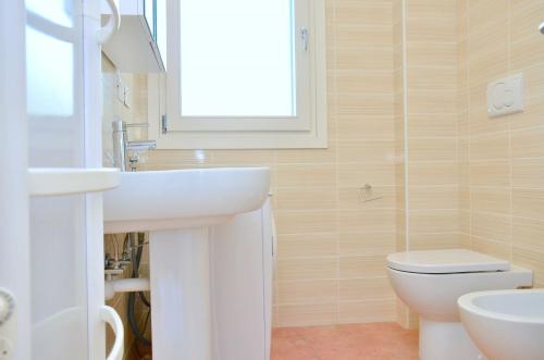 baño con lavabo y aseo y ventana en Nice three bedroom apartment close to the sea, en Bibione