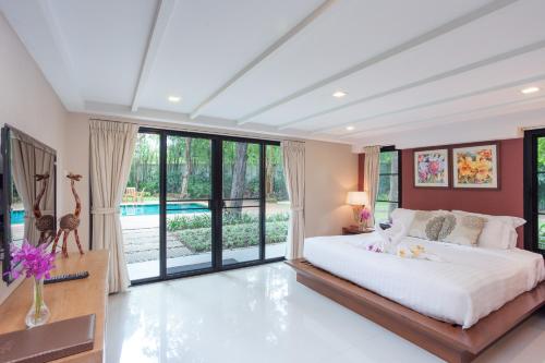 a bedroom with a large bed and large windows at Raya Resort Beach front - The Most Green Resort in Cha-am in Cha Am
