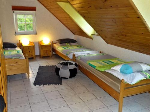 une chambre mansardée avec deux lits et deux fenêtres dans l'établissement Ferienhaus Schilz, à Plütscheid