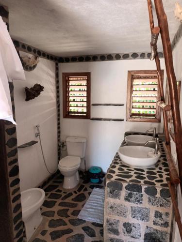 a bathroom with a toilet and a tub and a sink at Ravo Ravo Resort Nosy Be in Antafondro