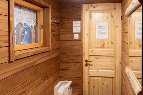 a wooden bathroom with a toilet and a window at Hillankukka in Äkäslompolo
