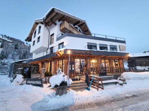 budynek z śniegiem na ziemi przed nim w obiekcie SKILL Mountain Lodge - Ski und Bike Hostel im Sommer mit JOKER CARD w Saalbach Hinterglemm