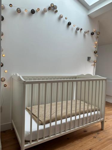 a white crib in a room with a ceiling at La Croisée des Vignobles - Gîte Fins Bois 