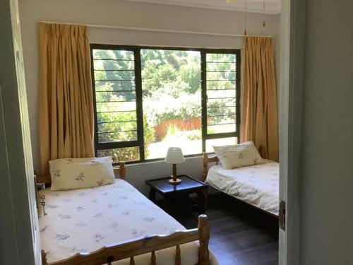 two beds in a room with two windows at The Bell's in the Berg in Underberg