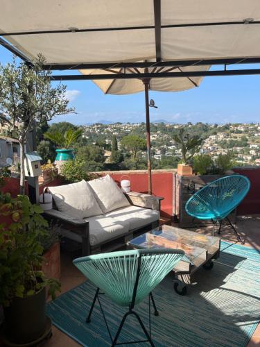 a patio with a couch and an umbrella at Bed & Breakfast Les Hauts de Cagnes vue mer et montagne in Cagnes-sur-Mer