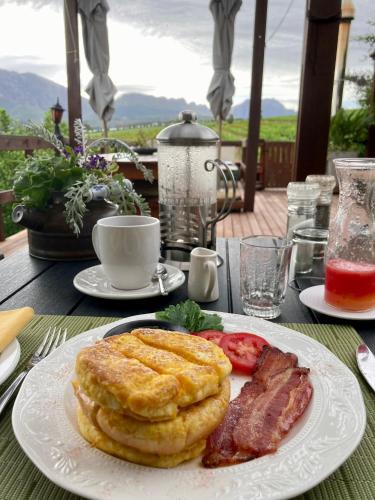 a plate of food with bacon and pancakes on a table at Wellington Country House in Wellington