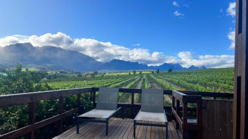 a deck with two chairs and a view of a vineyard at Wellington Country House in Wellington
