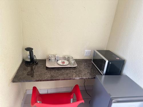 a small kitchen with a red chair and a microwave at MBT Guesthouses in Ga-Mothiba