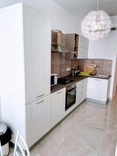una cucina con mobili bianchi e un lampadario di Kebu Rentals a San Giuliano