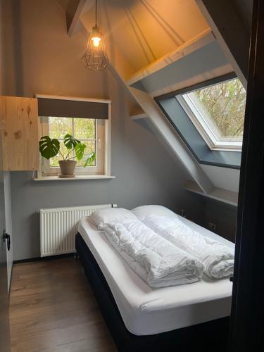 a bedroom with a bed in a attic with a window at Vakantiehuis Hof Molenzicht in Oostkapelle