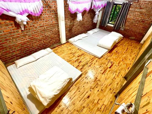 two beds in a room with wooden floors and pink decorations at Riverside Homestay in Cao Bằng