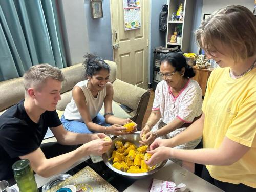 a group of people standing around a table eating food at KIRTIPUR COMFORT HOMESTAY with breakfast & dinner in Kirtipur