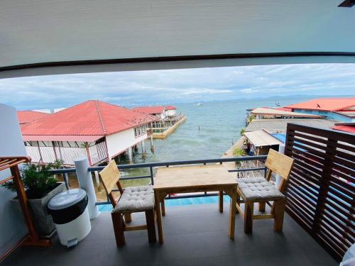 einen Balkon mit einem Tisch, Stühlen und Meerblick in der Unterkunft บ้านพักการ์ฟิลด์ ซีวิว เกาะล้าน in Ko Larn