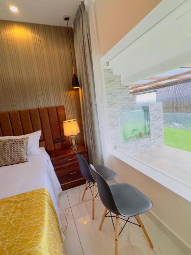 a bedroom with a bed and two chairs and a window at Misty Wonders in Munnar