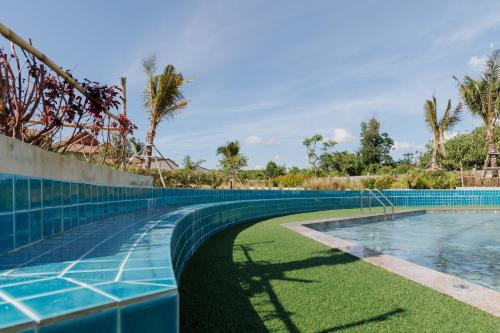 a swimming pool with grass and palm trees at Southern Airport Hotel Hatyai in Hat Yai