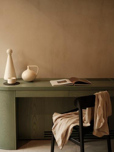 a green desk with a vase and a chair at Ethos Retreat Imerovigli, Santorini in Imerovigli