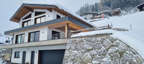 a house with a garage in the snow at Apartment Talblick in Bramberg am Wildkogel