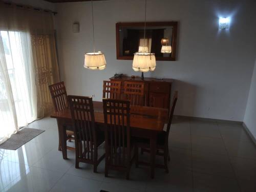 a dining room with a table and chairs and a mirror at Appartement charmant logpom in Douala