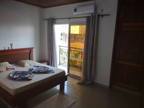 a bedroom with a bed and a door to a balcony at Appartement charmant logpom in Douala