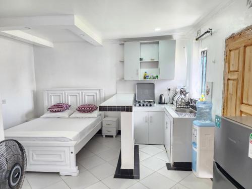 a small white kitchen with a bed and a sink at Swift Haven Studio Bamburi in Mombasa