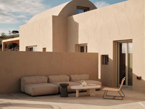 a couch and a table in front of a building at Ethos Retreat Imerovigli, Santorini in Imerovigli