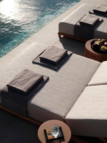 a row of beds next to a swimming pool at Ethos Retreat Imerovigli, Santorini in Imerovigli