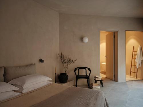 a bedroom with a bed and a chair at Ethos Retreat Imerovigli, Santorini in Imerovigli