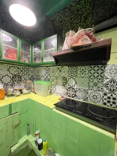 a kitchen with green and white tiles on the wall at Lyna House in Hanoi