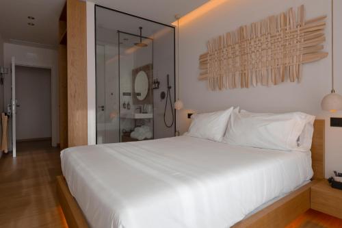 a bedroom with a large white bed and a mirror at Malates Slow Boutique Hotel in Foz
