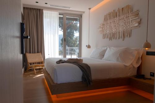 a bedroom with a large white bed with a balcony at Malates Slow Boutique Hotel in Foz