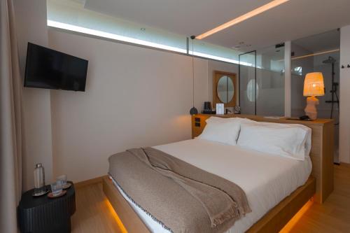 a bedroom with a bed with a television on the wall at Malates Slow Boutique Hotel in Foz