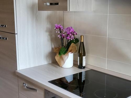 a bottle of wine and a vase with purple flowers on a counter at Relais Garden Lecco in Valmadrera