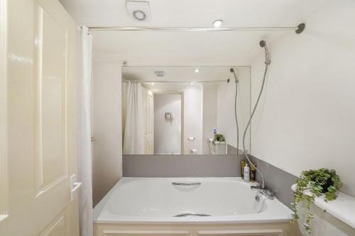 ein weißes Badezimmer mit einem Waschbecken und einem Spiegel in der Unterkunft LiveStay - Apartments in Bayswater London in London