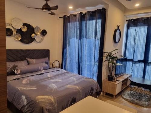 a bedroom with a bed and blue curtains and a table at HarbourBay Residence. Batam. Studio. 1min to Ferry in Jodoh