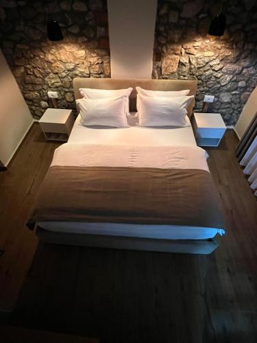 a large bed in a bedroom with a stone wall at Vila Ndrio in Pogradec