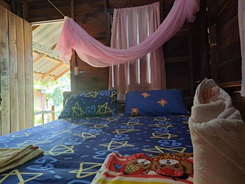 a bedroom with a bed with a blue comforter at Rasta House,,Koh Phayam in Ko Phayam