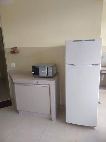 a white refrigerator next to a counter with a microwave at Alto padrão !Forno Pizza! Hidro !Vista linda! in Poços de Caldas