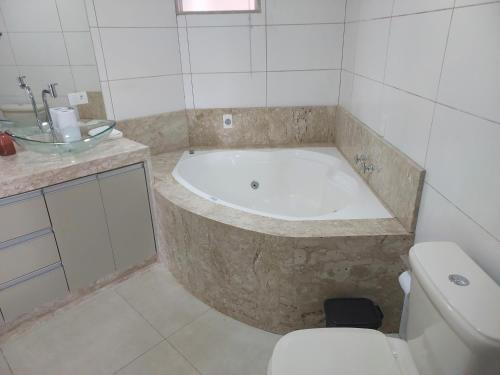 a bathroom with a bath tub and a toilet at Alto padrão !Forno Pizza! Hidro !Vista linda! in Poços de Caldas