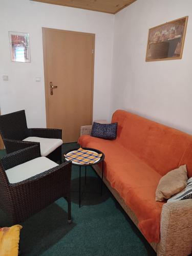 a living room with an orange couch and chairs at Privat Mária in Liptovský Ján