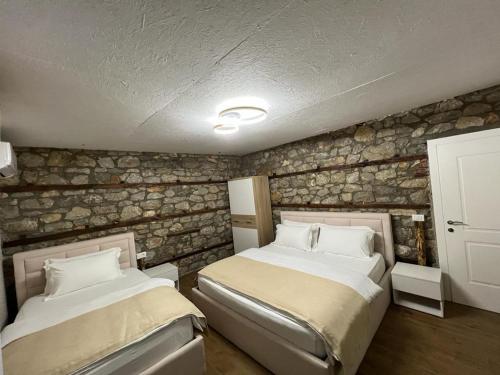 two beds in a room with a stone wall at Vila Ndrio in Pogradec