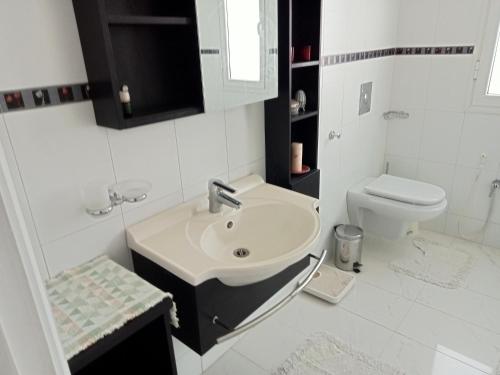 a white bathroom with a sink and a toilet at Chez Mme Jaouida in El Mourstane