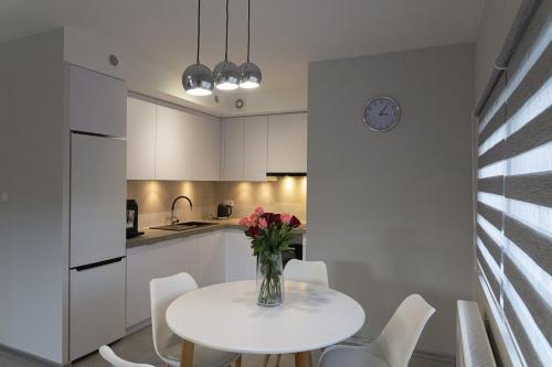 een witte keuken met een tafel met een vaas met bloemen erop bij VacationClub – Spokojna 24I Apartament 1 in Wisła