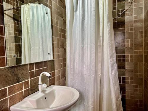 La salle de bains est pourvue d'un lavabo et d'un rideau de douche. dans l'établissement The Wild Farms By Gwestai, à Masinagudi