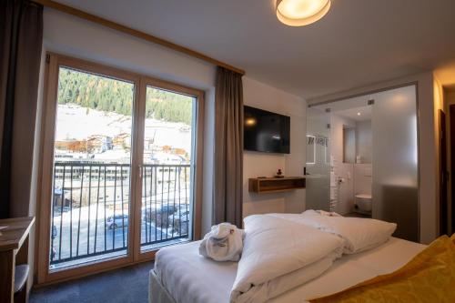 um quarto com uma cama e uma grande janela em Alpenresidenz Trisanna em Ischgl