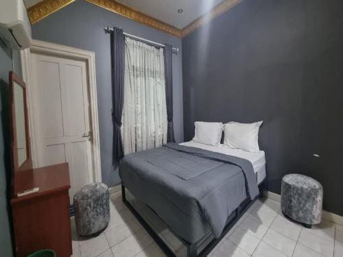 1 dormitorio con 1 cama con 2 taburetes y una ventana en Villa Kota Bunga EE3-15, en Cikundul