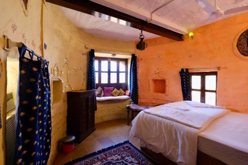 ein Schlafzimmer mit einem Bett und einer Bank in einem Zimmer in der Unterkunft Saffron Homestay in Jaisalmer
