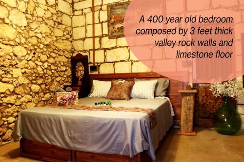 una camera con un letto in una parete in pietra di Il-Bàrraġ Farmhouse B&B - Gozo Traditional Hospitality a Nadur