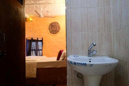 a bathroom with a sink and a bed in a room at Saffron Homestay in Jaisalmer